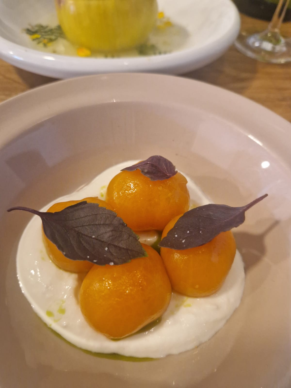 Peeled orange tomatoes on a bed of curd, dressed with purple basil leaves